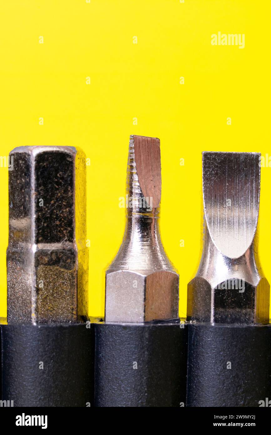 Screwdriver bits in a row on yellow background close up Stock Photo