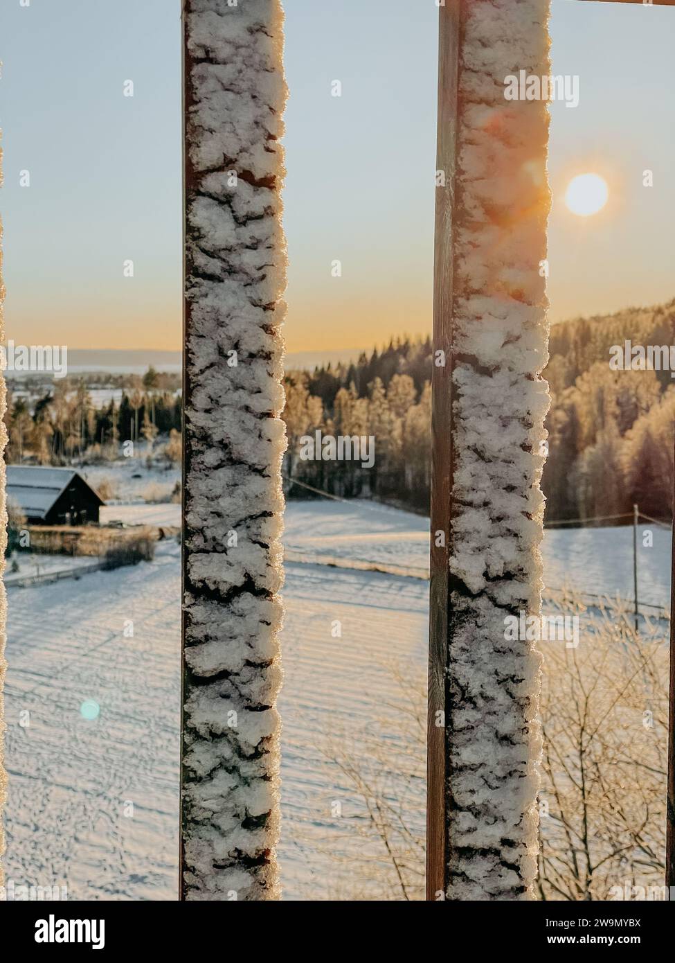 View of winter landscape through a snowy fence, Baerum, Akershus, Norway Stock Photo