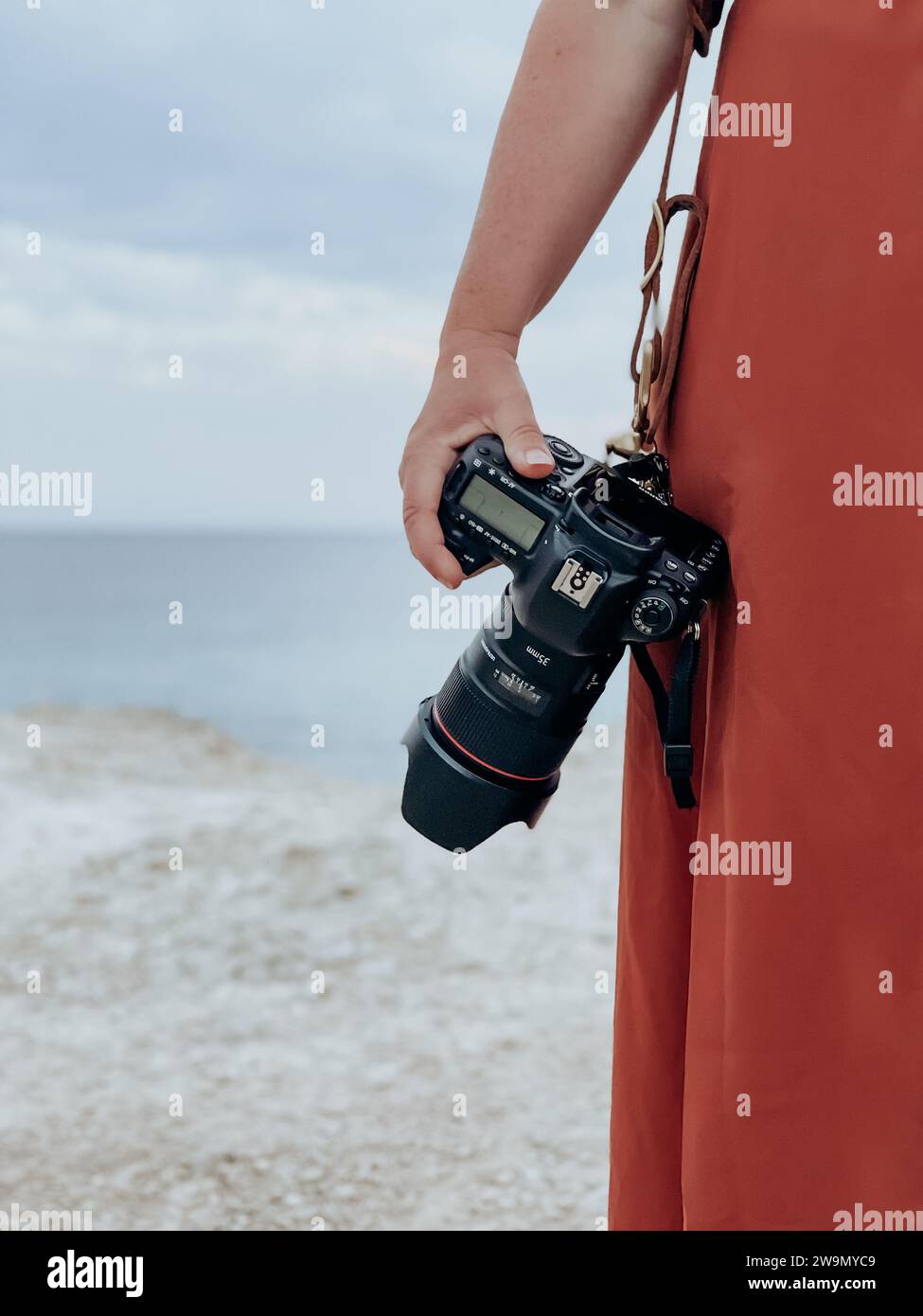 Close-up of a woman standing on a beach holding a digital single-lens reflex camera, Majorca, Spain Stock Photo