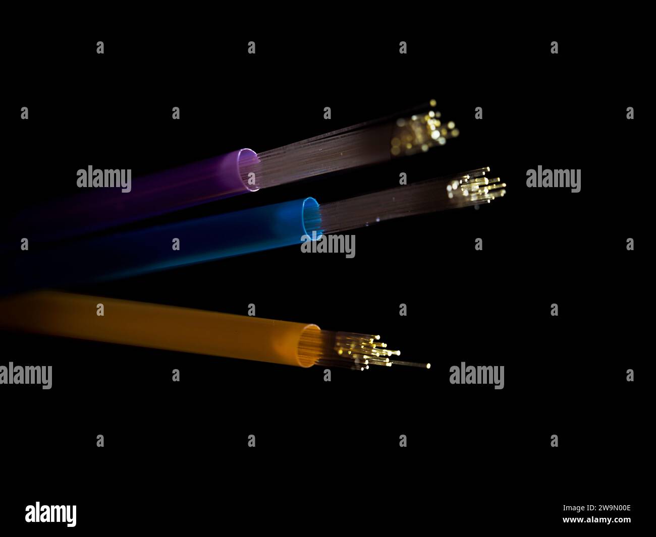 Fibre optic LED lights threaded through three straws against a black background Stock Photo