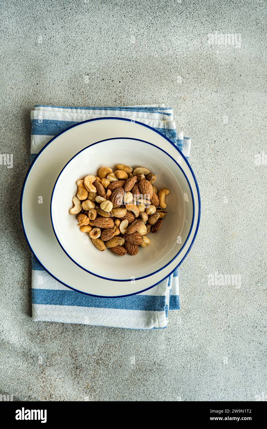 Overhead view of a bowl of salted almond, cashew and hazelnuts on a table Stock Photo