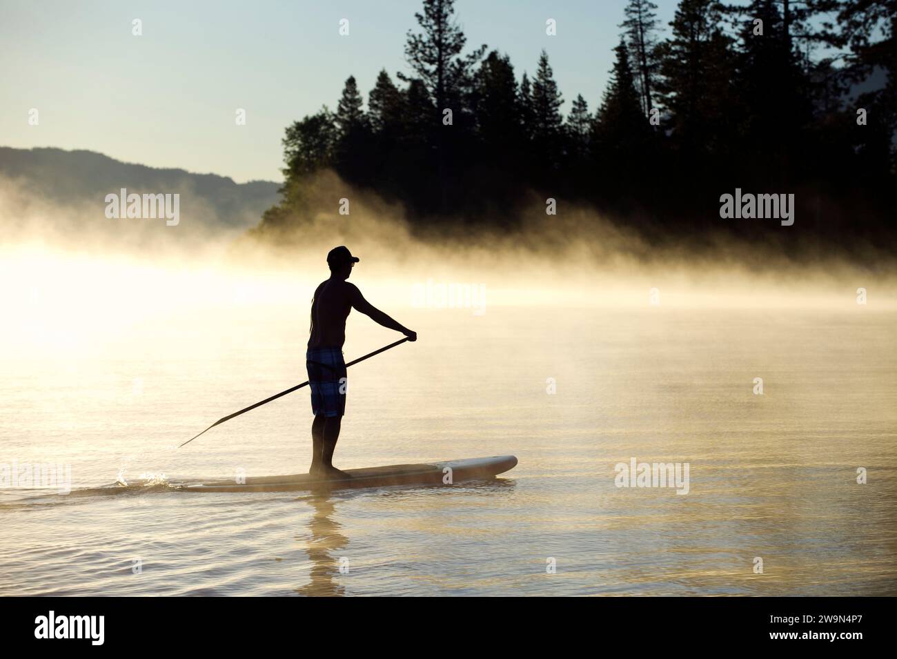A man Stand Up Paddleboards (SUP) on Lake Tahoe at sunrise silhouetted