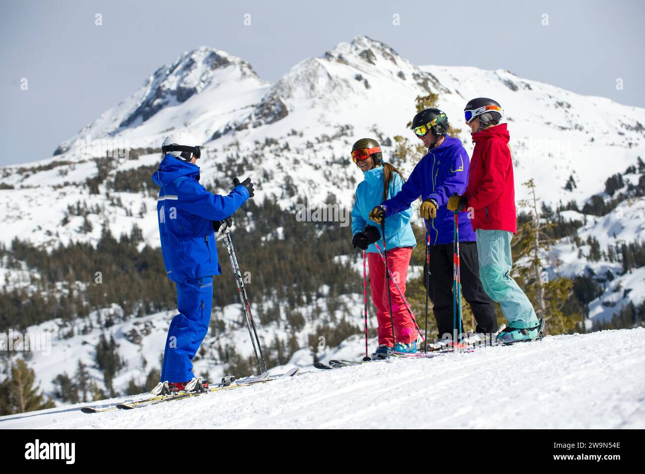 A group of skiers gather around and listen to their ski instructor in the winter at Kirkwood Mountain Resort in Kirkwood, California. Stock Photo