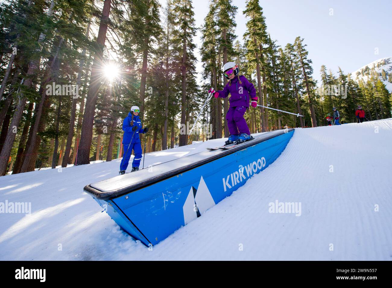 A young skier jibs a box in the terrain park while their ski instructor looks on during a lesson at Kirkwood Mountain Resort in Kirkwood, California. Stock Photo