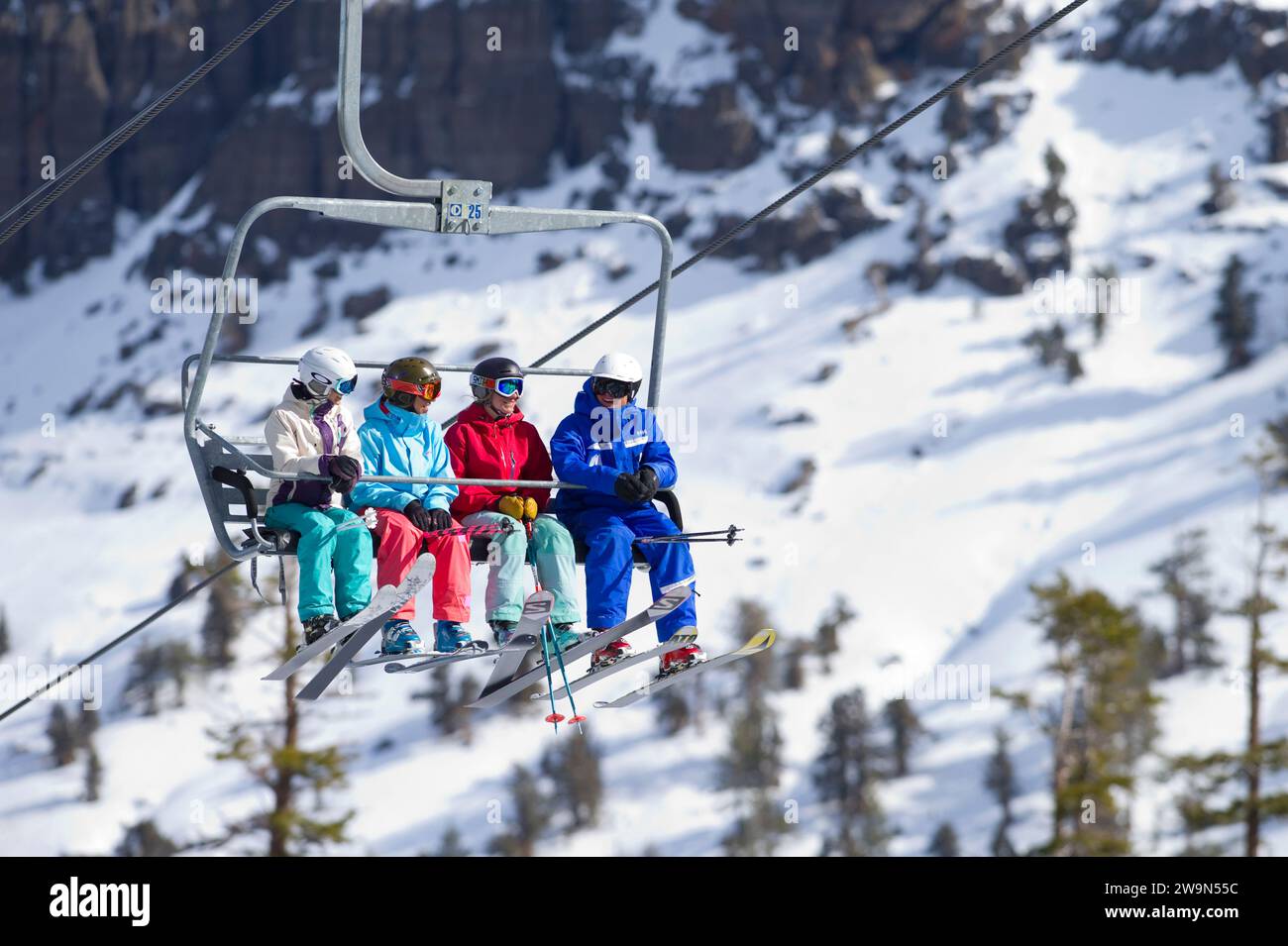 A group of women ride the chairlift with their ski instructor in the winter at Kirkwood Mountain Resort in Kirkwood, California. Stock Photo