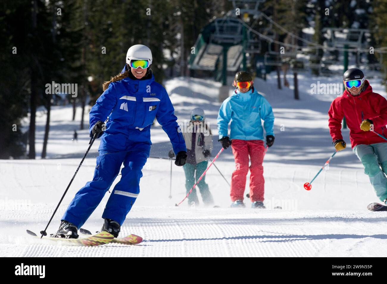 A group of women skiers follow their ski instructor down a groomed trail in the winter at Kirkwood Mountain Resort in Kirkwood, California. Stock Photo