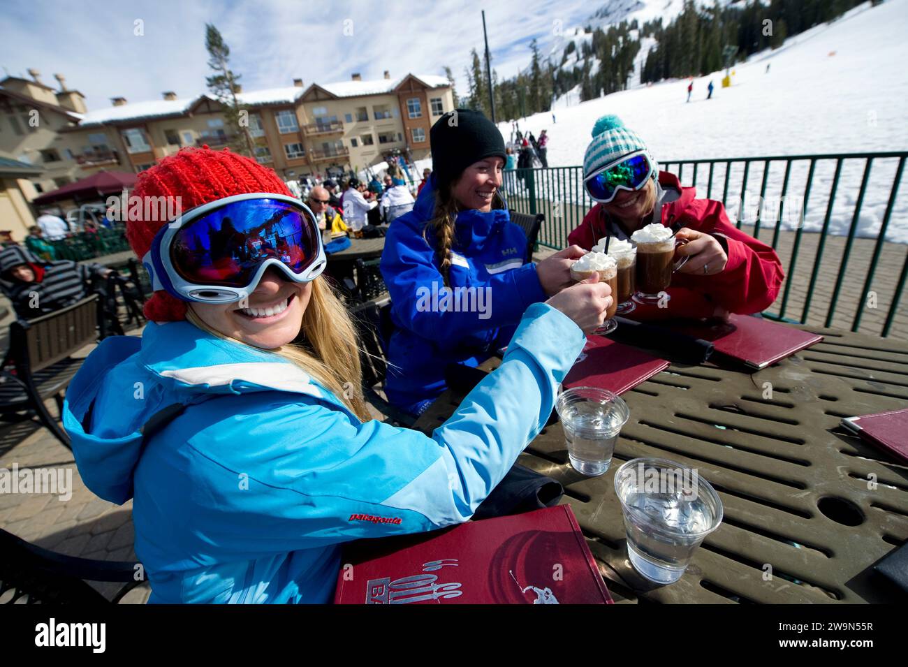 A group of female skiers sit and smile with their ski instructor drinking hot cocoa in the winter at Kirkwood Mountain Resort in Kirkwood, California. Stock Photo