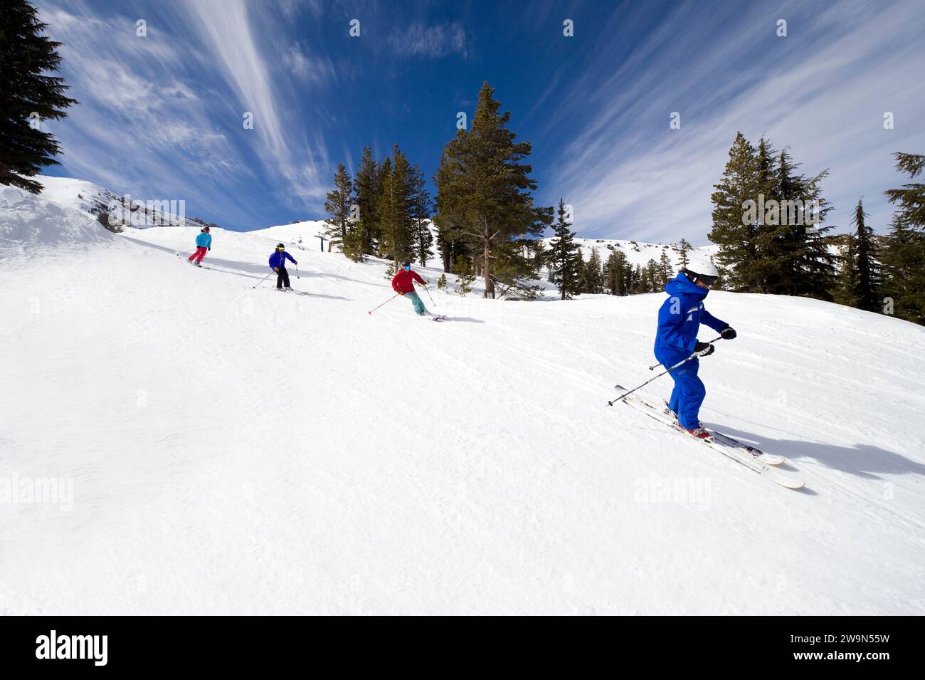A group of skiers follow their ski instructor down a groomed trail in the winter at Kirkwood Mountain Resort in Kirkwood, California. Stock Photo