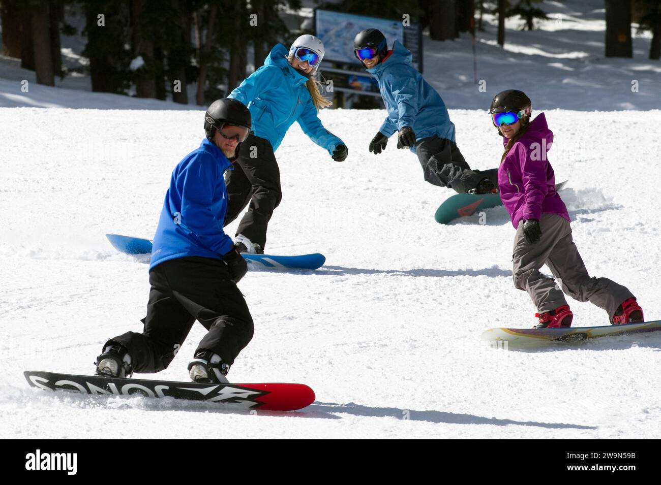 A group of snowboarders follow their snowboard instructor down a groomed trail in the winter at Kirkwood Mountain Resort in Kirkwood, California. Stock Photo