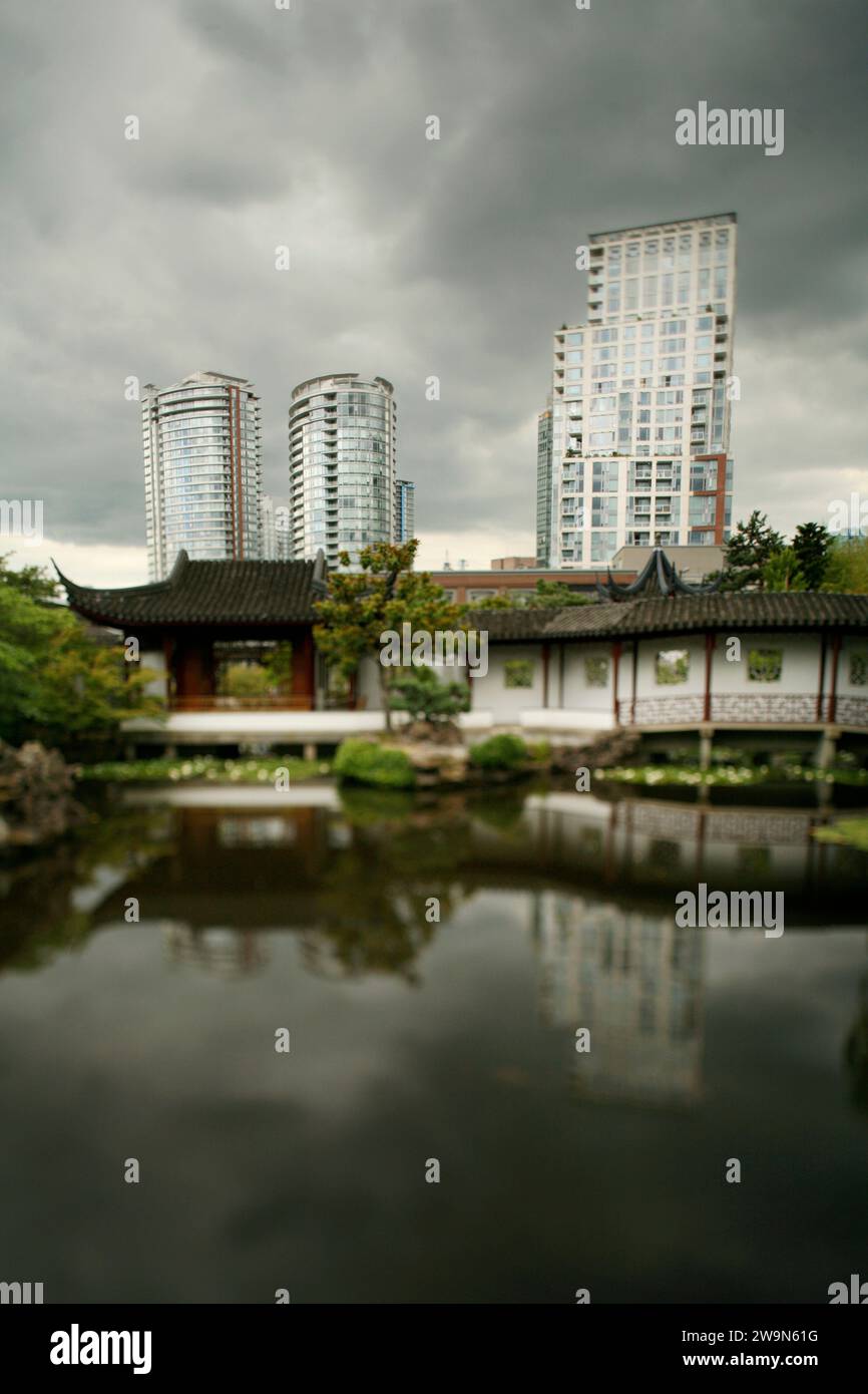 A traditionally styled Japanese water garden sits in front of the backdrop of modern buildings in downtown Vancouver, British Co Stock Photo