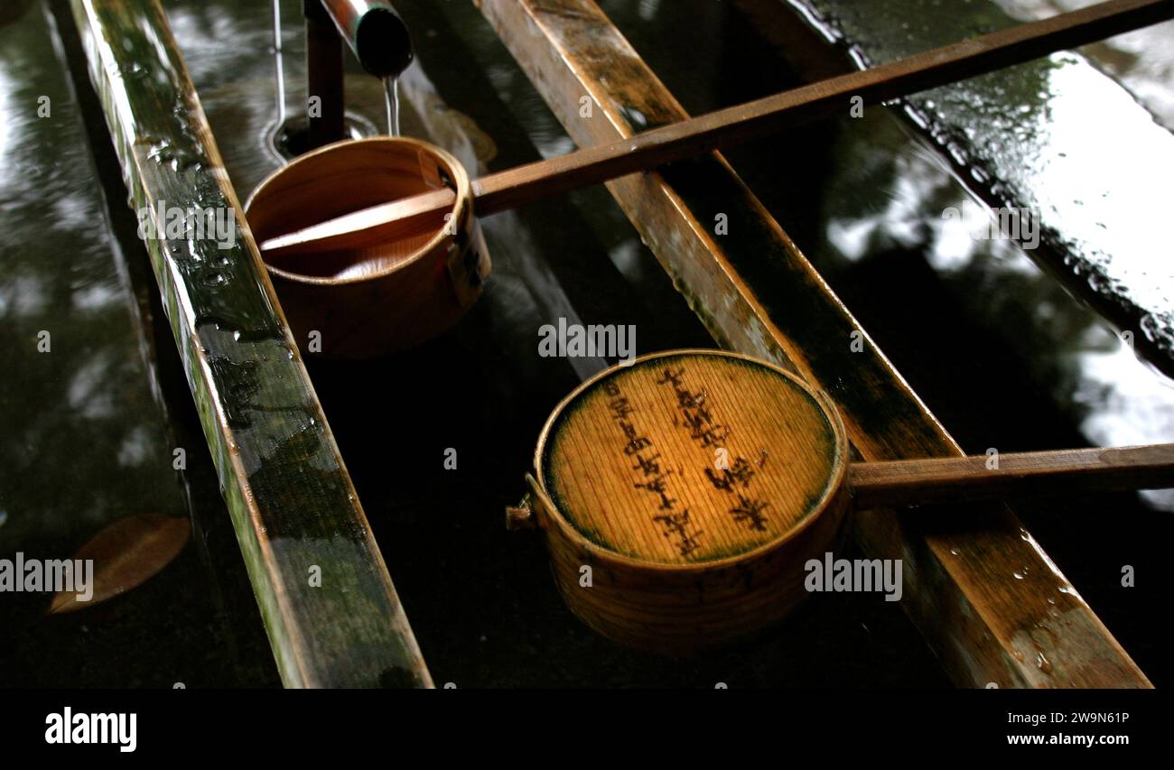 Two Japanese bamboo ladles rest in a fountain of a Shinto temple in