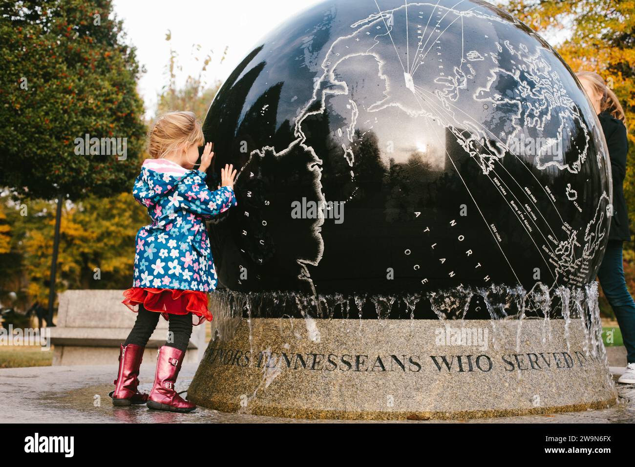 World globe map outdoor sculpture with girl in raincoat Stock Photo