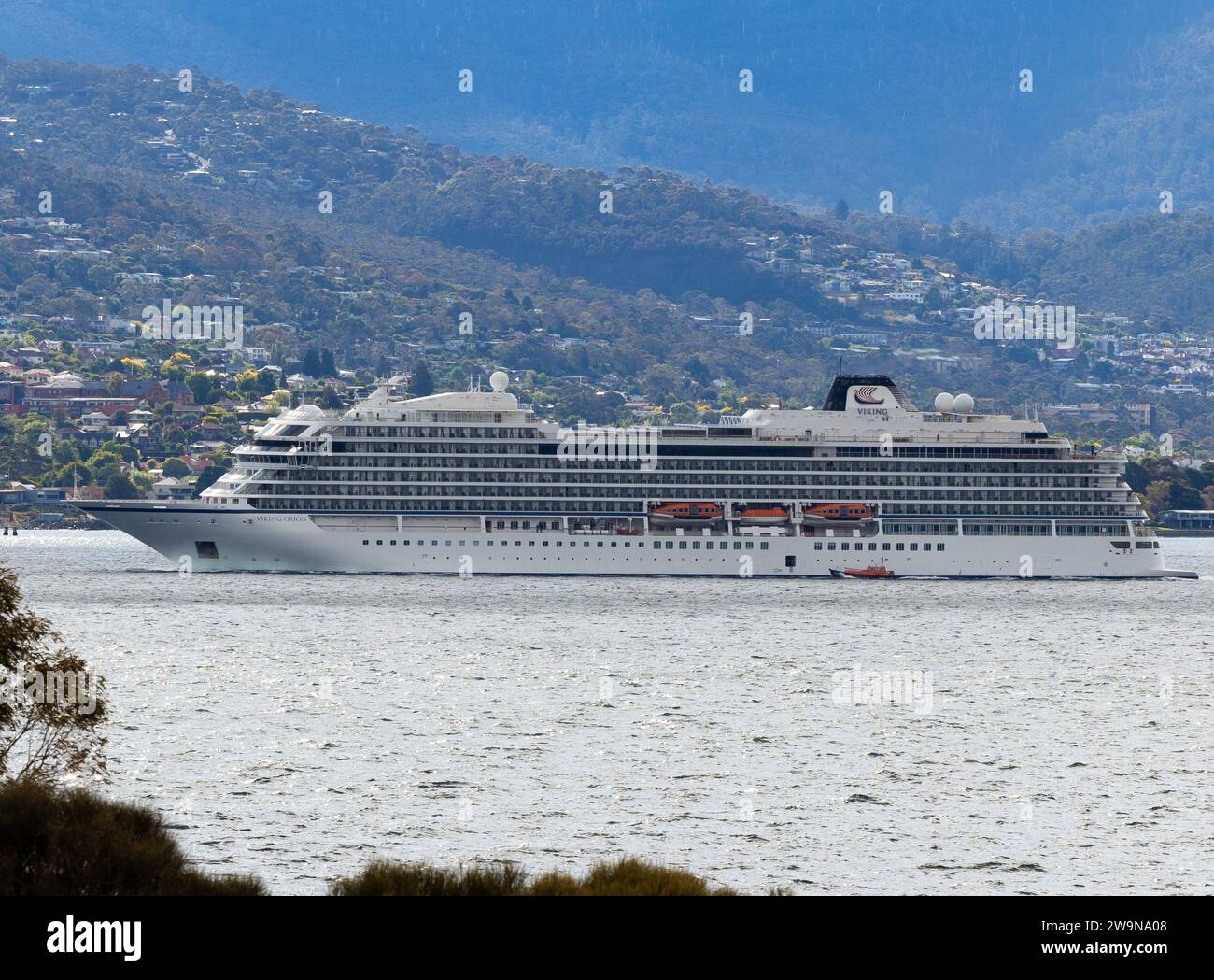 Viking Orion passenger cruise ship in profile or side on, departing Hobart, Tasmania along the Derwent River 12/28/2023. Whole ship with Sandy Bay and Stock Photo