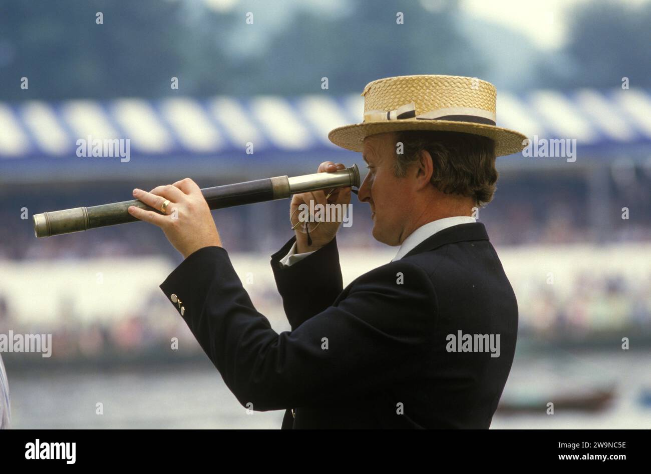 Henley Royal Rowing Regatta. A gent in a straw boater watching the racing through a telescope. Henley on Thames, Oxfordshire, England July 1985 1980s UK HOMER SYKES Stock Photo
