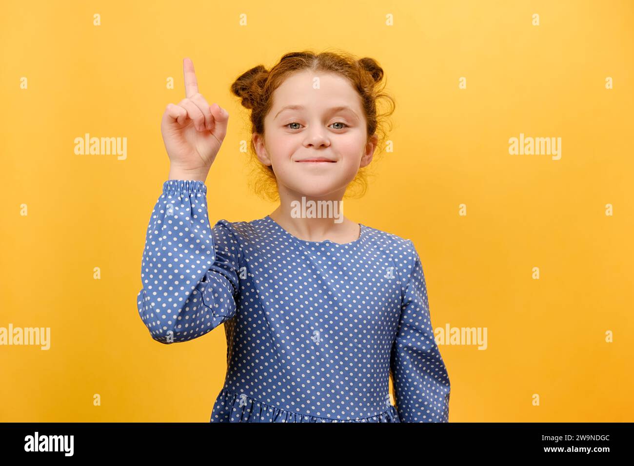 Portrait of inspired preteen girl child with open mouth pointing finger up in inspiration, having solution for problem, posing isolated over plain yel Stock Photo