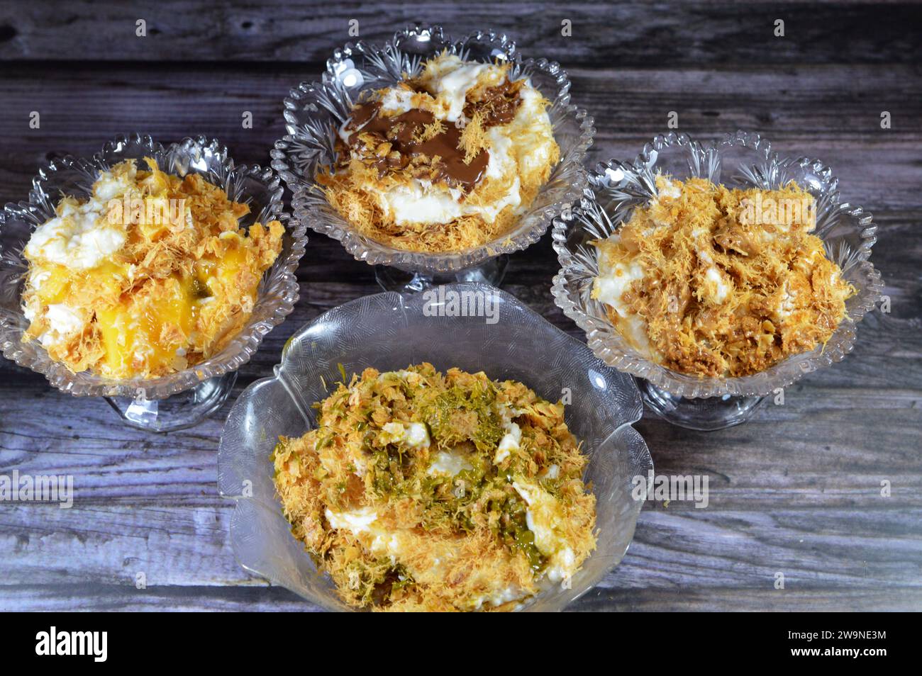 Sweet Koshary recipe in Egypt made of multi layers of rice with milk sweet pudding, whipped cream, toasted Konafa and phyllo filo, with pistachio sauc Stock Photo