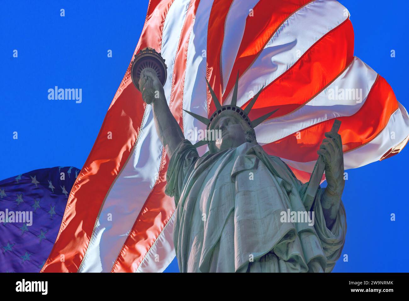 Statue of Liberty with beautifully waving star and stripes American flag background Stock Photo