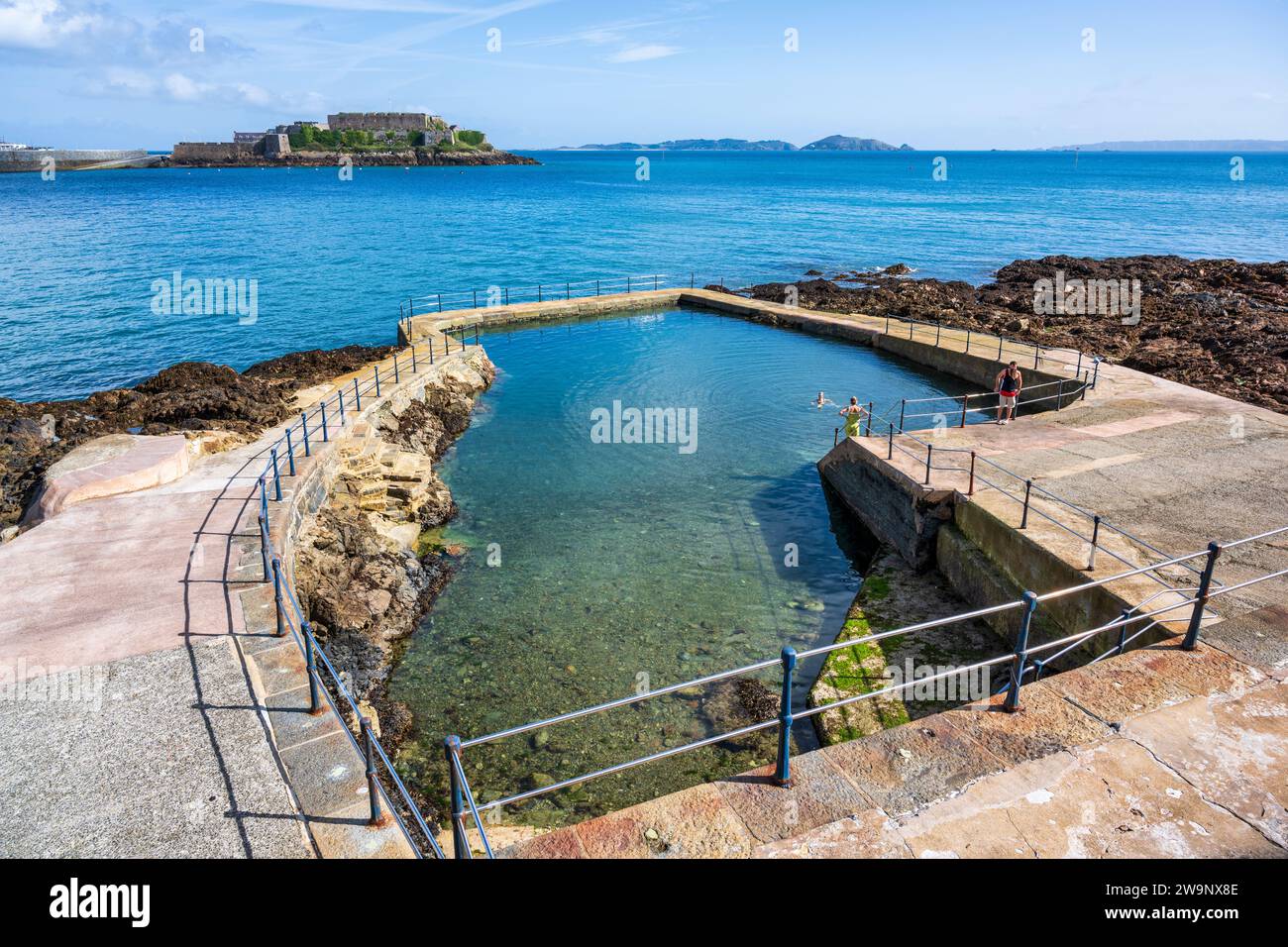 La Vallette Gent's Outdoor swimming pool, with Castle Cornet in distance, in St Peter Port, Guernsey, Channel Islands Stock Photo
