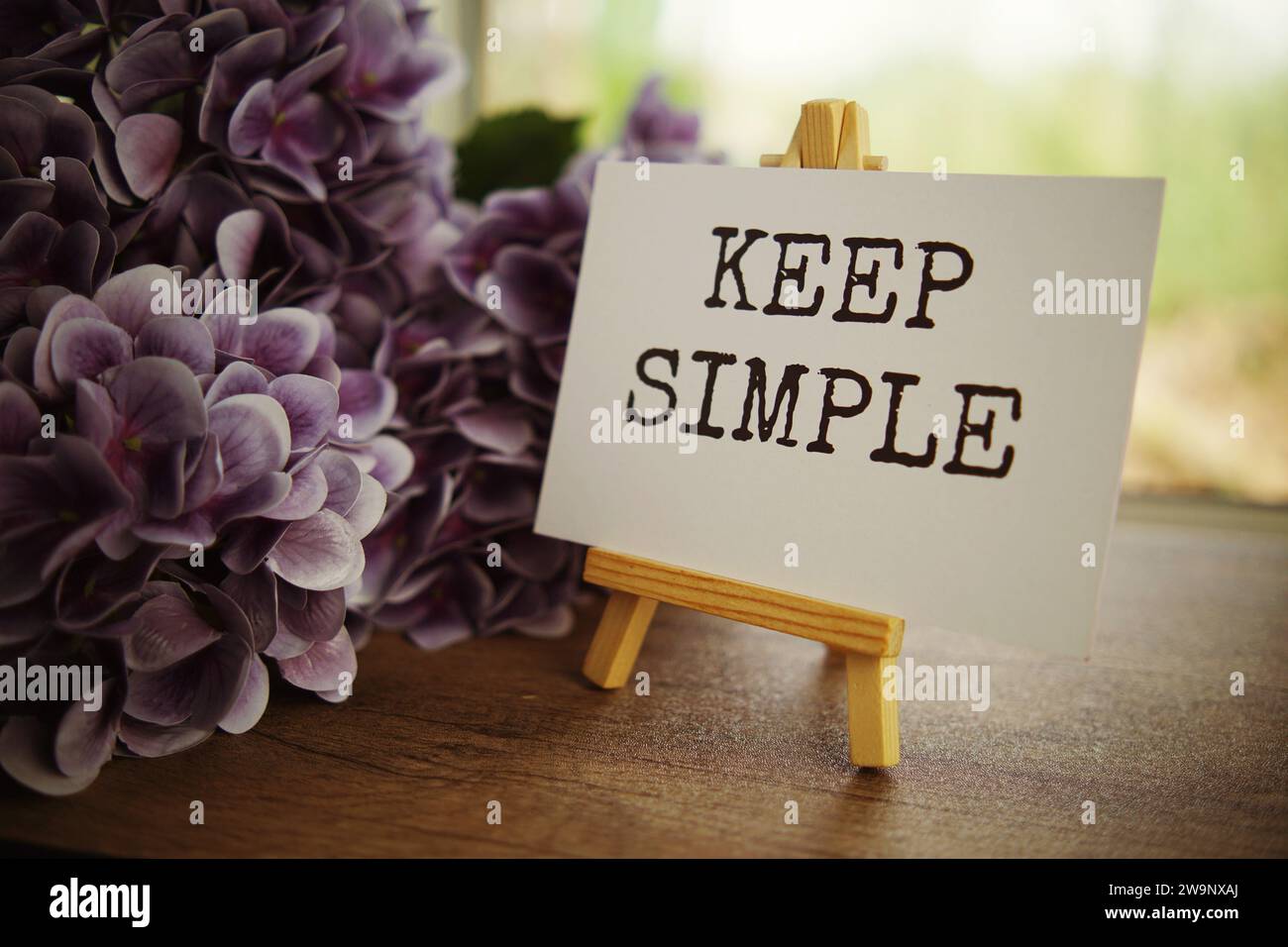 Keep simple text message text message on paper card with wooden easel on wooden table background, inspiration motivation concept Stock Photo