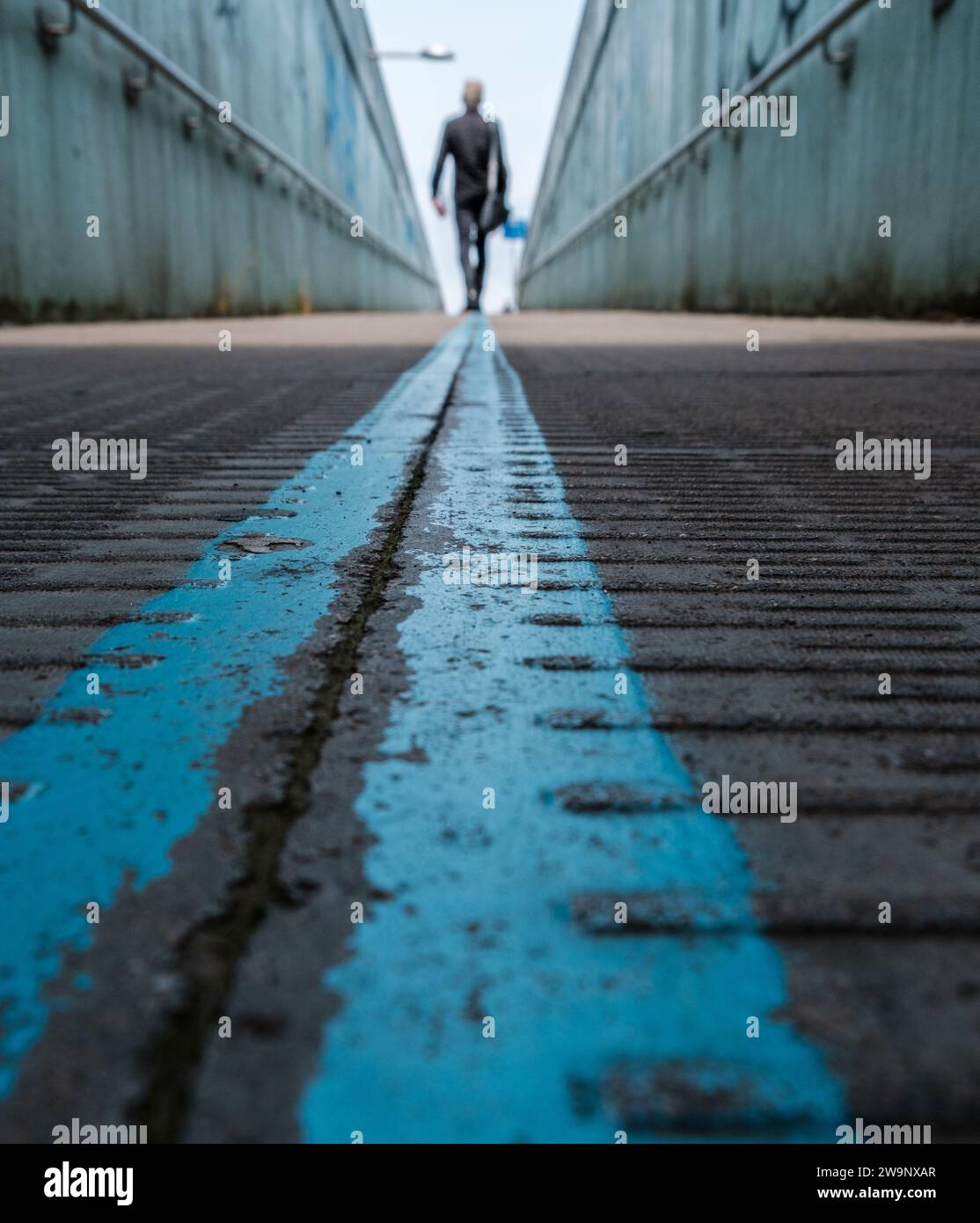 Person walking away on a walkway with high walls on both sides with