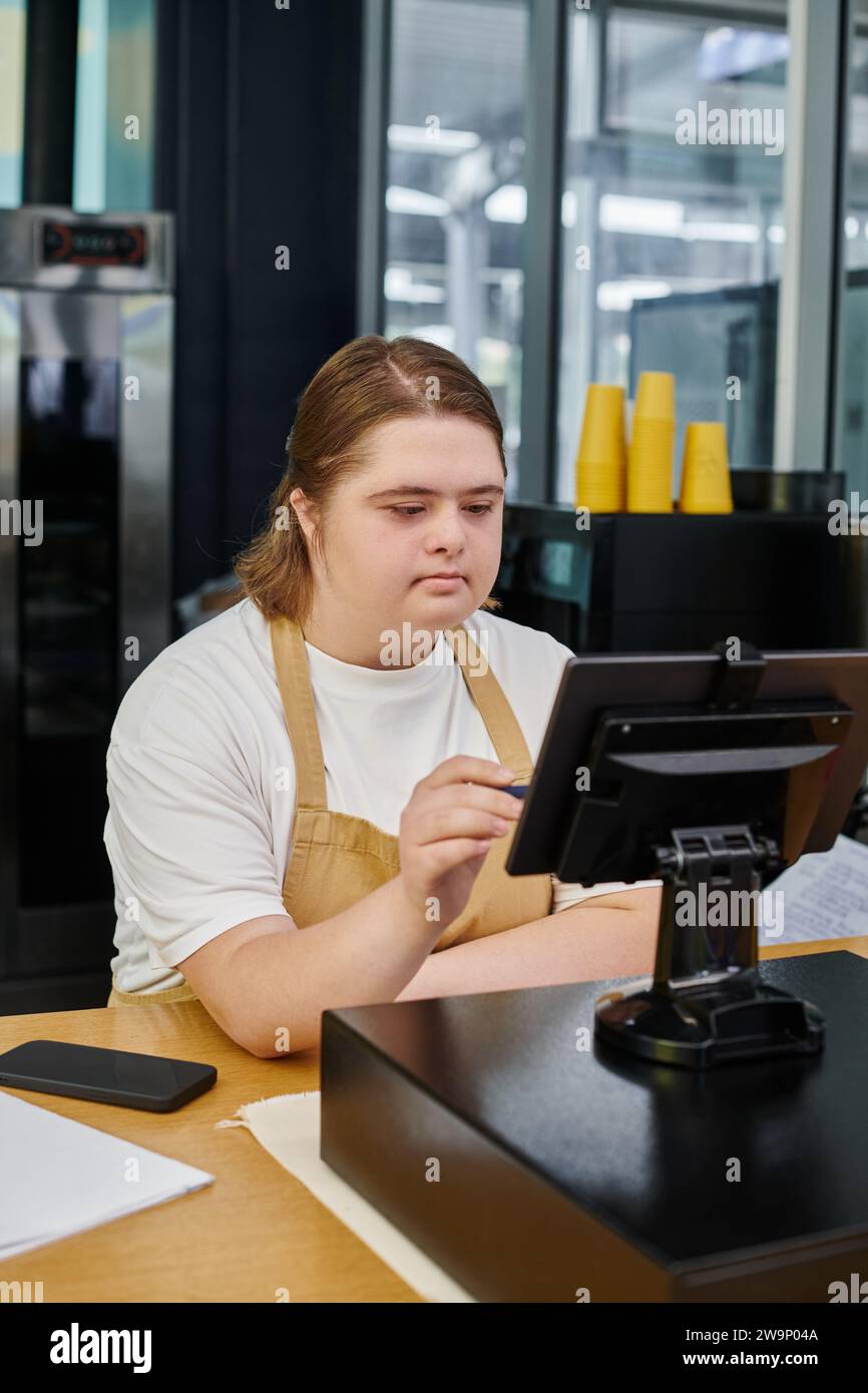 young woman with down syndrome operating cash terminal on counter in ...