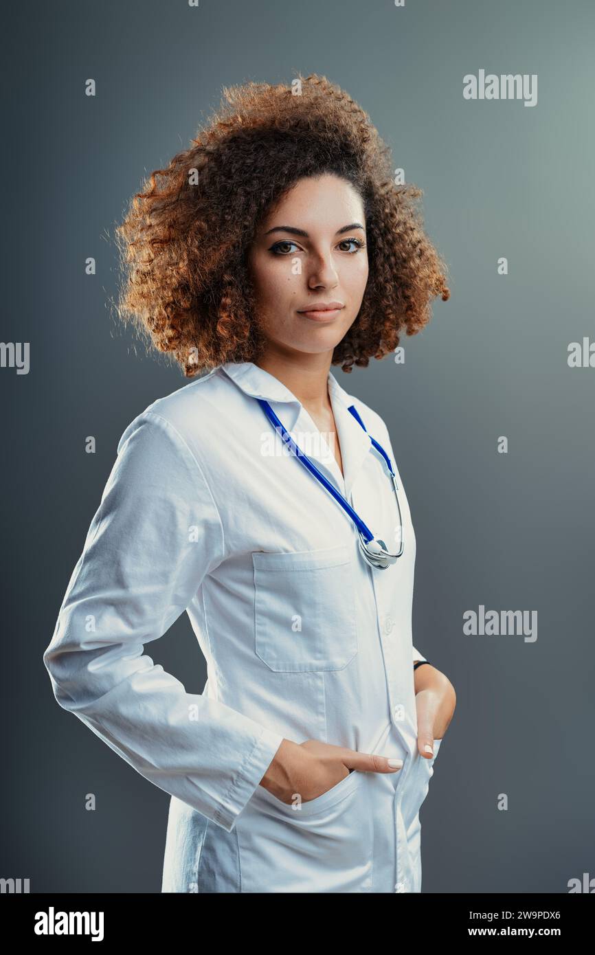 Professional woman in a lab coat stands confidently, her curly hair ...