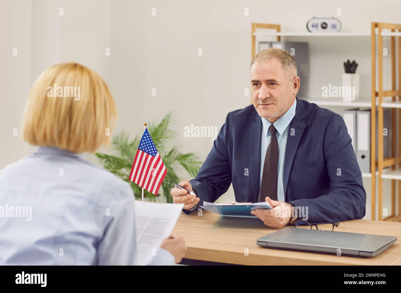 USA Consulate or Immigration Services worker talking to woman about visa or immigration Stock Photo