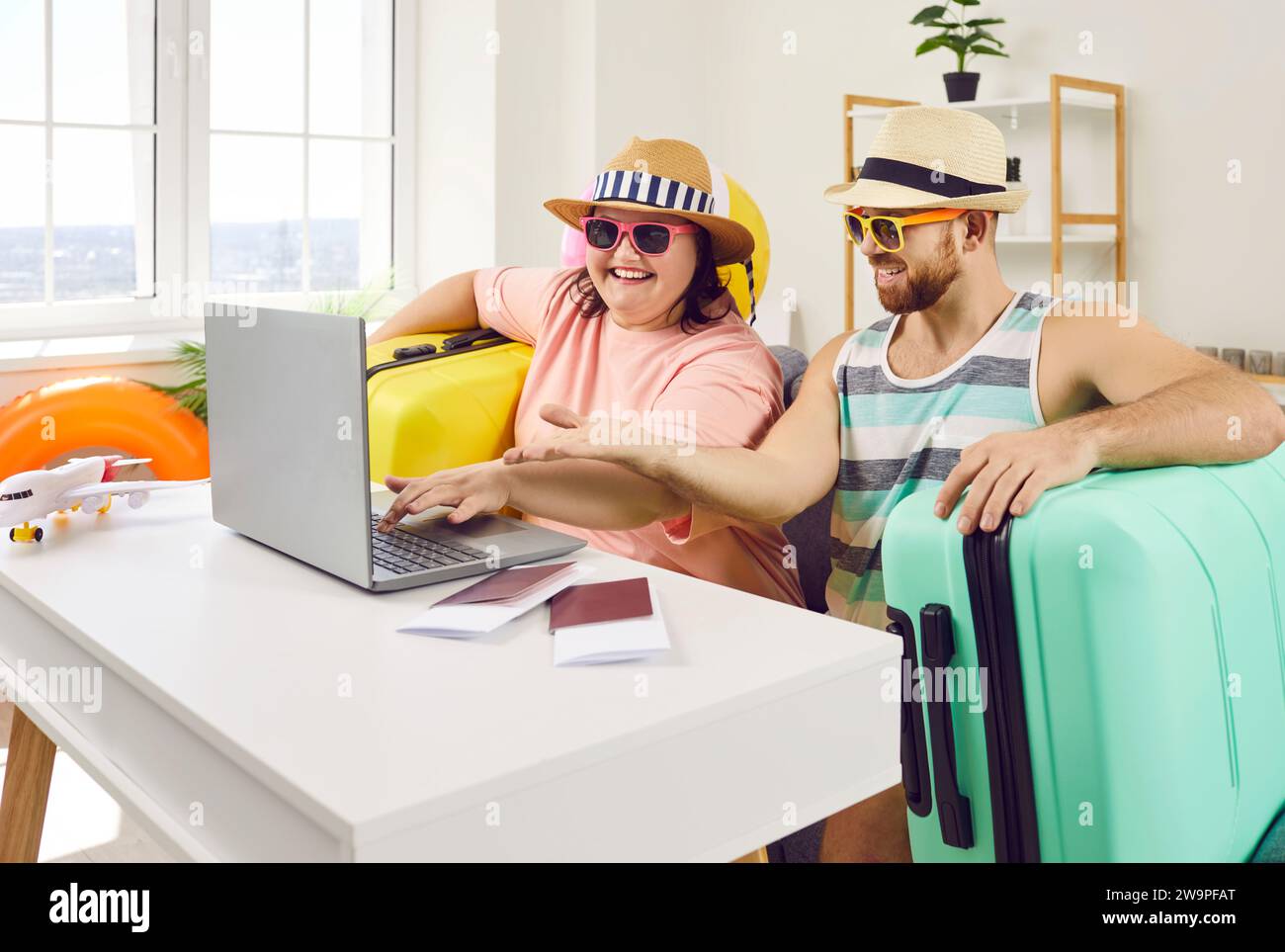 Funny couple planning vacation trip while sitting at home with packed suitcases Stock Photo