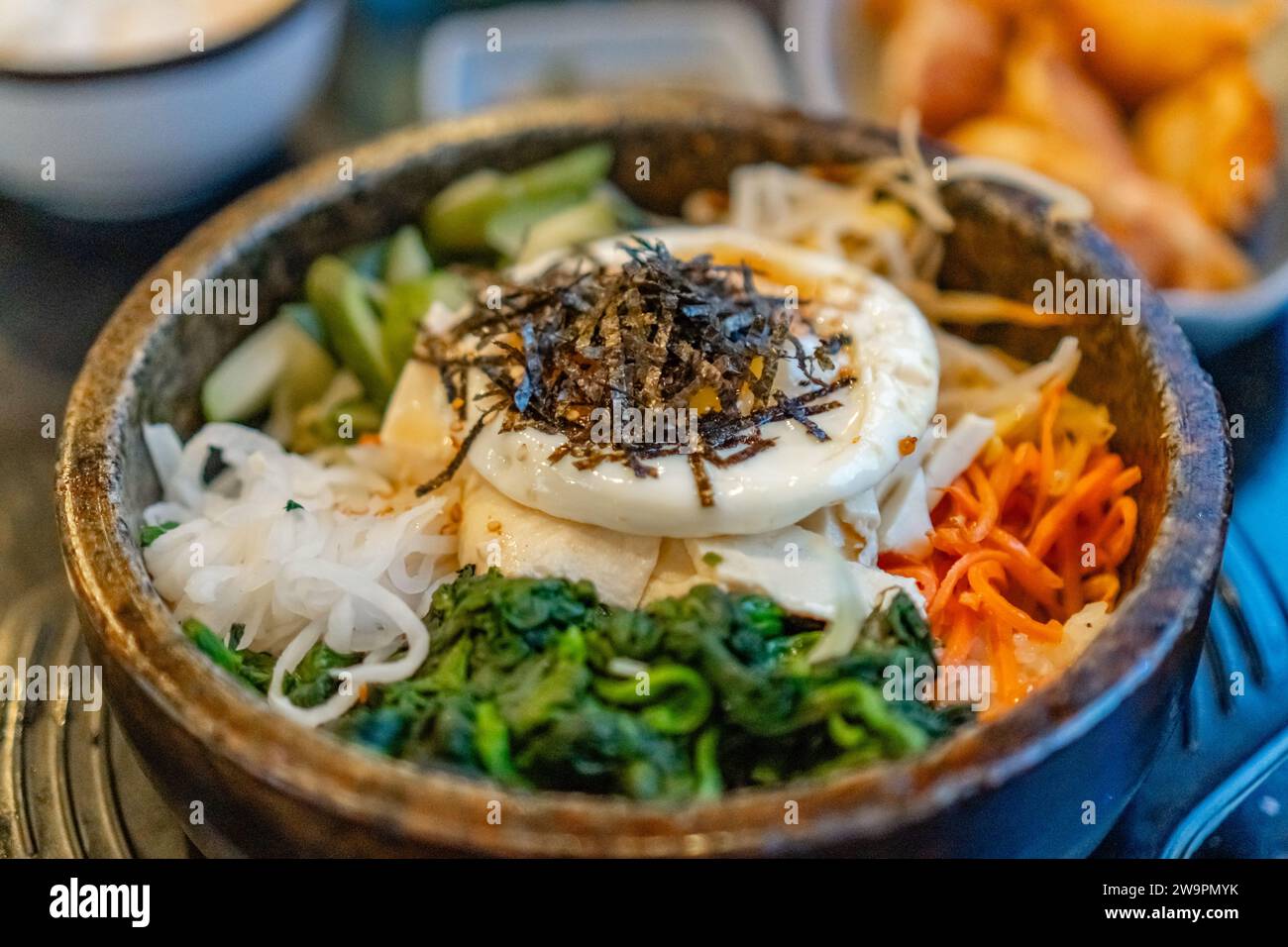 Korean vegetarian bibimbap, fried tofu and vegetables sered in a hot