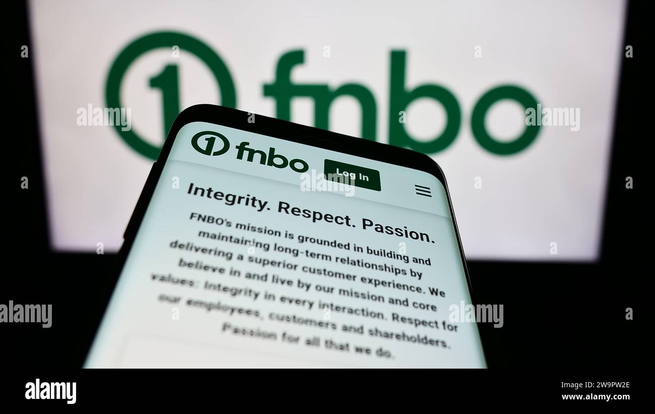Mobile phone with website of US financial company First National Bank Omaha (FNBO) in front of business logo. Focus on top-left of phone display. Stock Photo