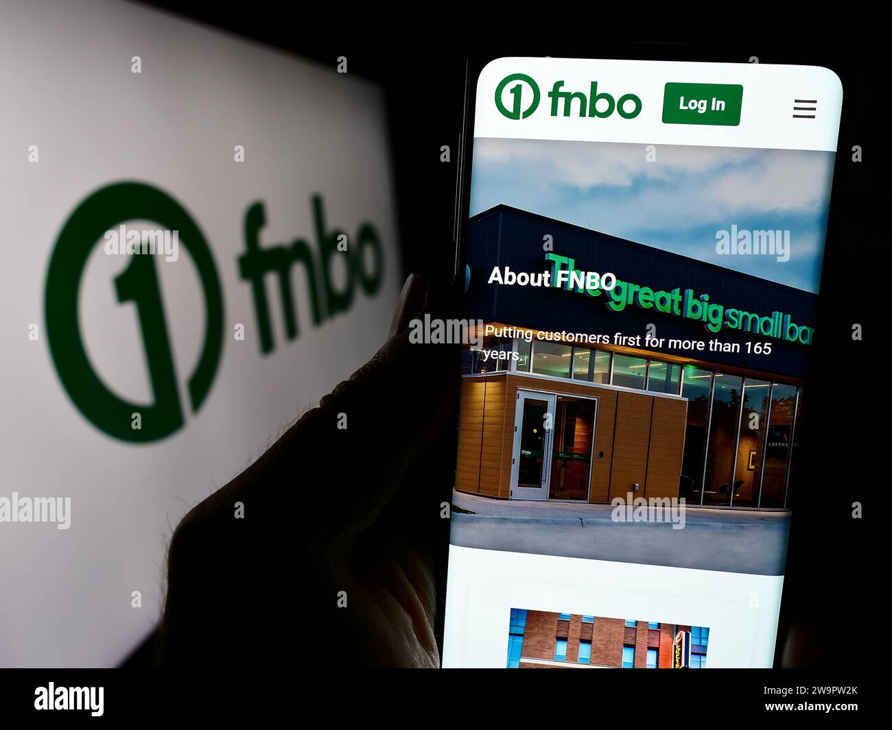 Person holding cellphone with website of US financial company First National Bank Omaha (FNBO) in front of logo. Focus on center of phone display. Stock Photo