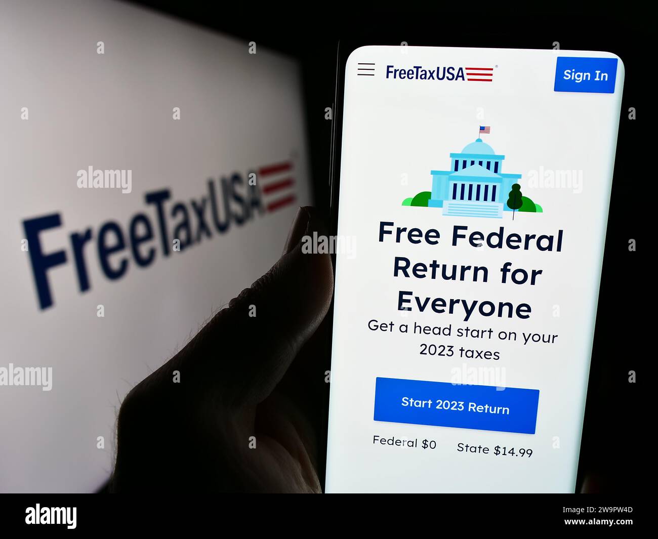 Person holding cellphone with webpage of US online tax software company