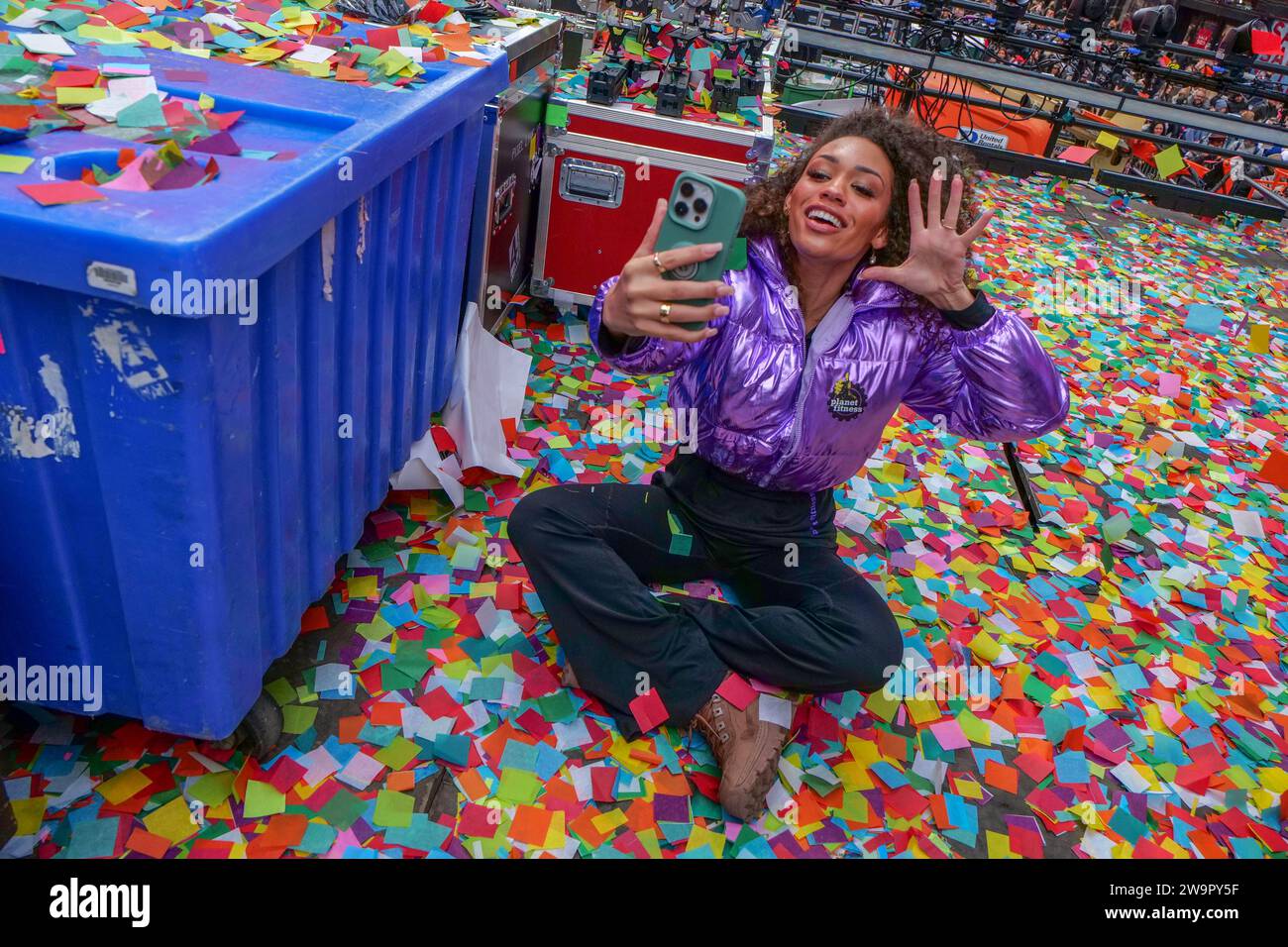 New York, New York, USA. 29th Dec, 2023. New Year's Eve organizers and presenting sponsor Planet Fitness test air worthiness of confetti in Times Square two days until New Year's Eve. Planet Fitness employee does selfie video while sitting in just tested confetti. (Credit Image: © Milo Hess/ZUMA Press Wire) EDITORIAL USAGE ONLY! Not for Commercial USAGE! Stock Photo