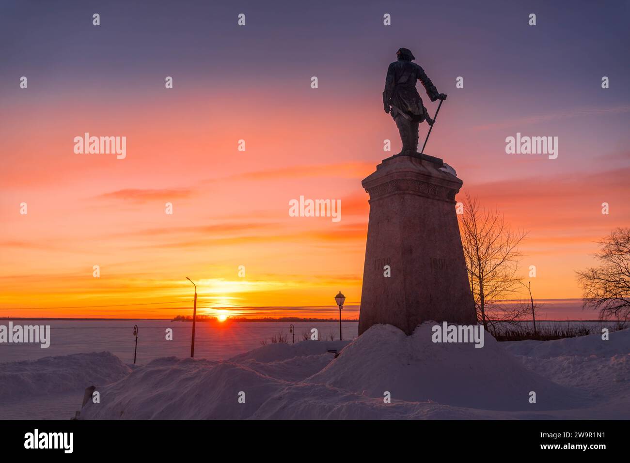 The monument of Russian Emperor Peter the Great (Peter I) in the Arkhangelsk waterfront during the colorful sunset on the cold snowy winter day in Rus Stock Photo