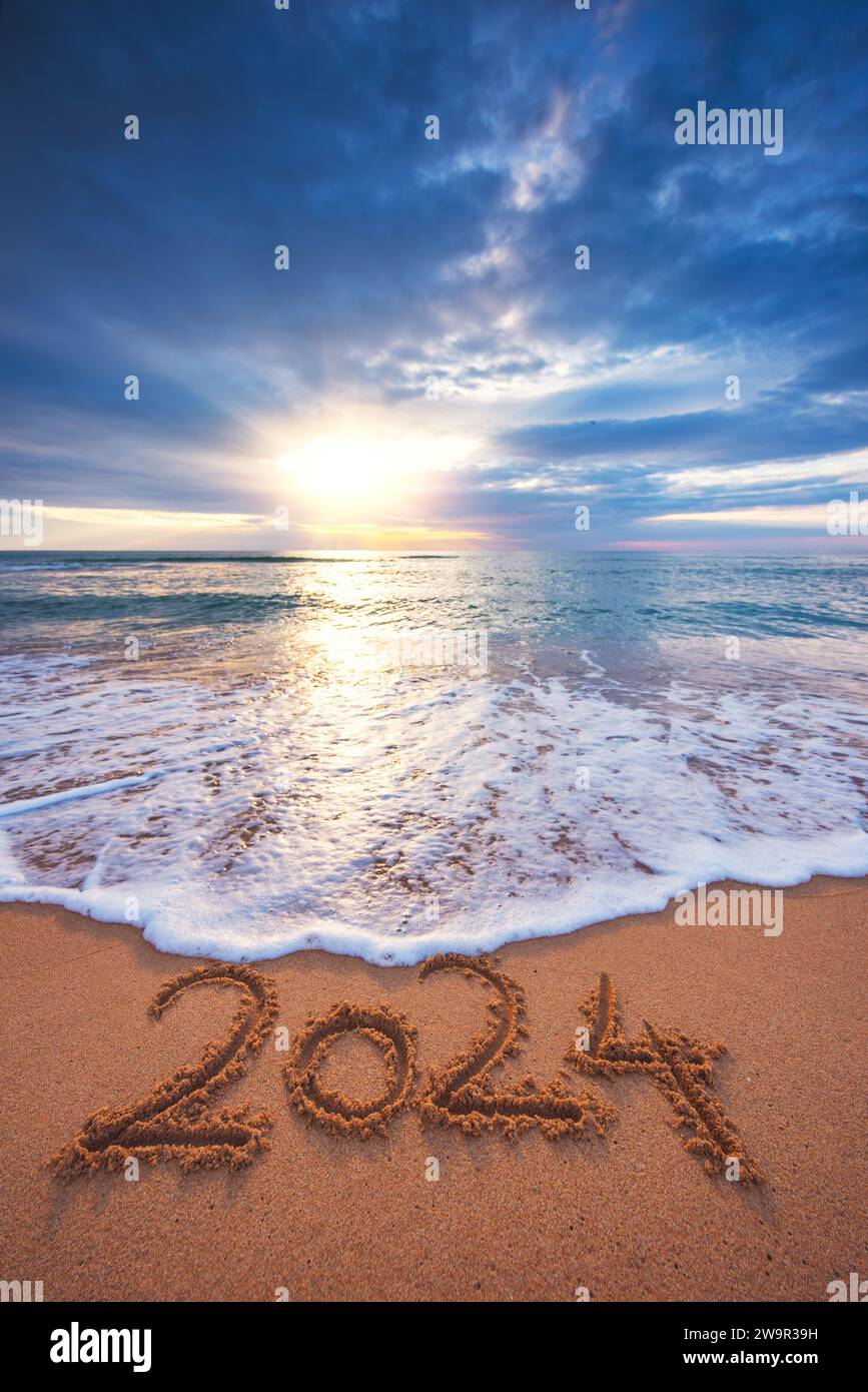 Happy New Year 2024 concept text on the beach sand at sunrise vertical nature landscape Stock Photo