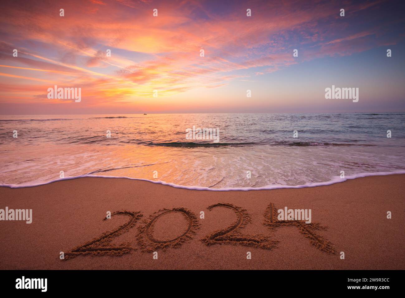 Happy New Year 2024 concept, lettering on the beach. Written text on the sea beach at sunrise. Stock Photo