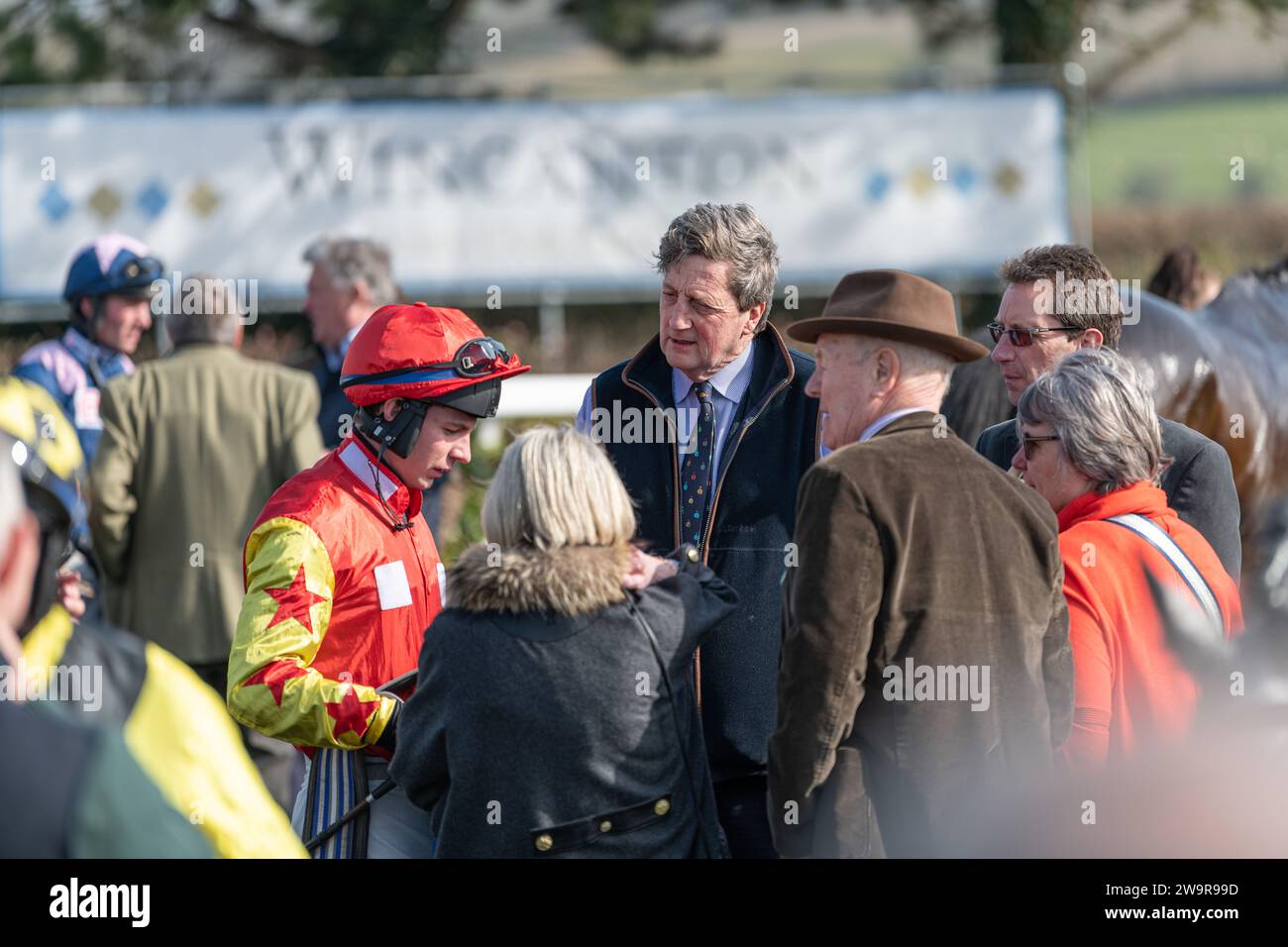Jockey Rex Dingle and Trainer Jeremy Scott meet with owners in the parade ground at Wincanton before racing Ballyblack Stock Photo