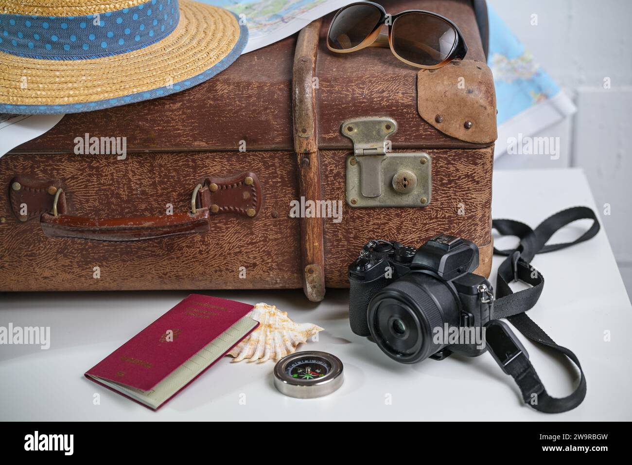 Old brown vintage suitcase with straw hat, photo camera, sunglasses, passport and a map, travel and summer vacation concept, copy space, selected focu Stock Photo