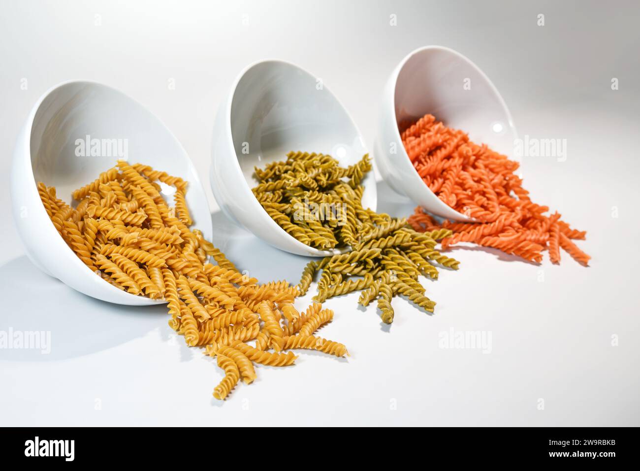 Three white bowls with different legume pasta fusilli made from chickpeas, mung beans and red lentils, diet alternative with less carbohydrates but mo Stock Photo