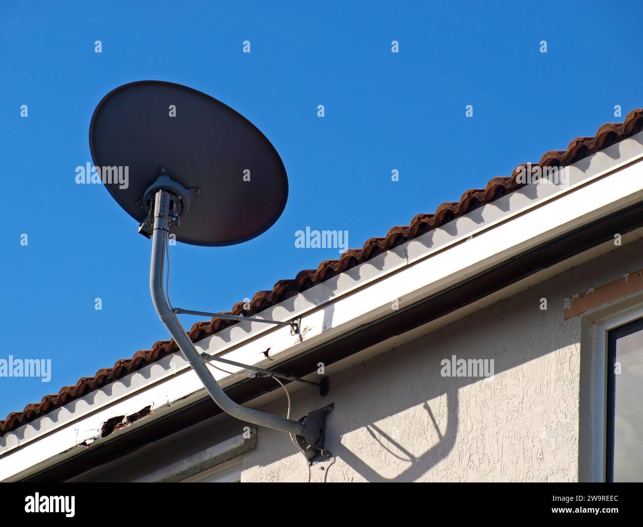 Satellite television antenna installed in building with the fascia damaged. Stock Photo