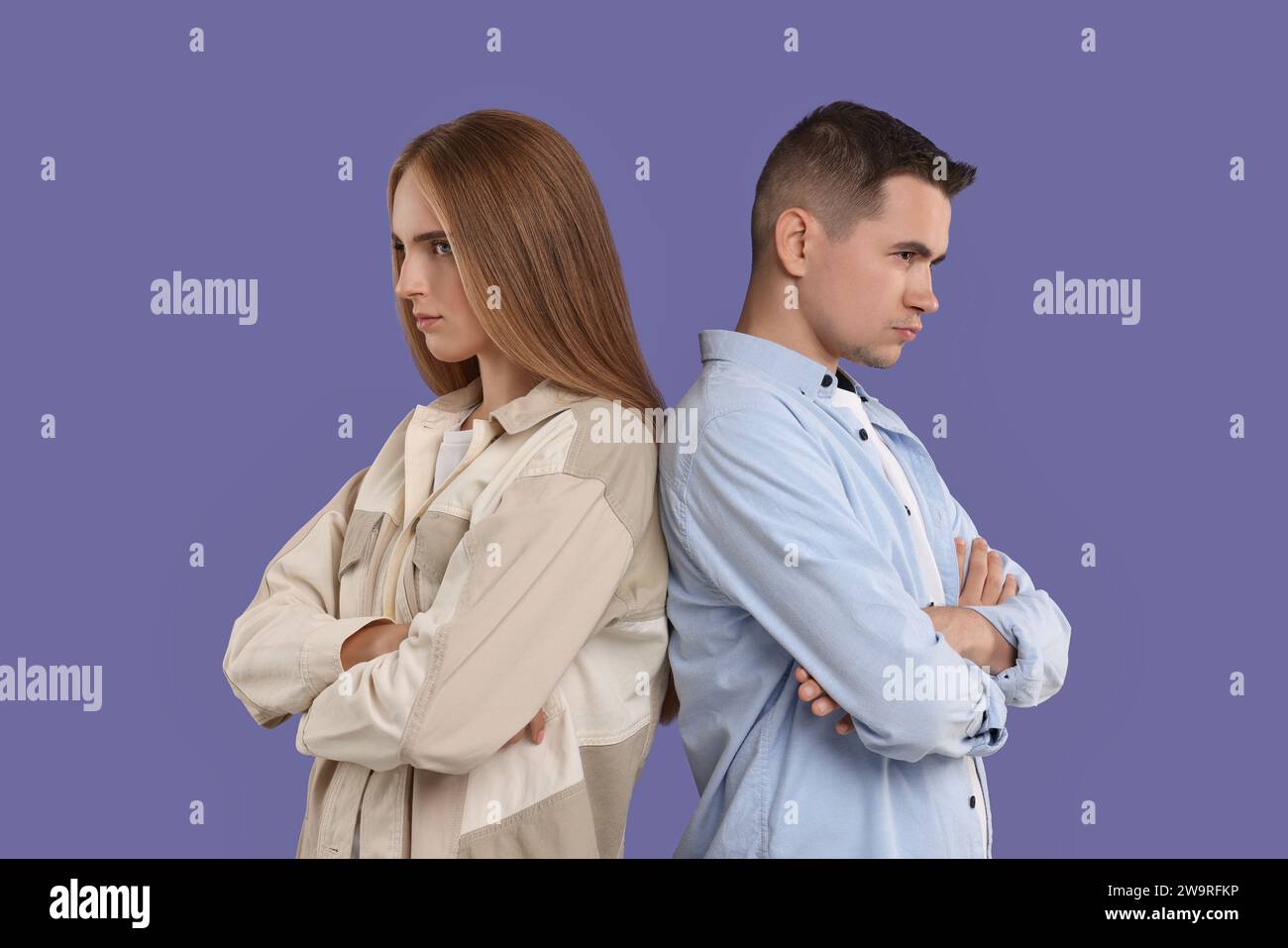 Portrait of resentful couple with crossed arms on violet background Stock Photo