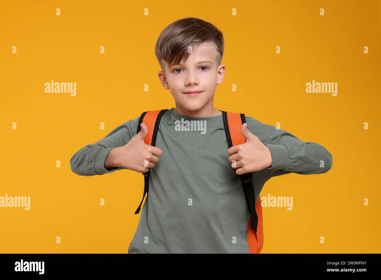 Cute schoolboy showing thumbs up on orange background Stock Photo - Alamy