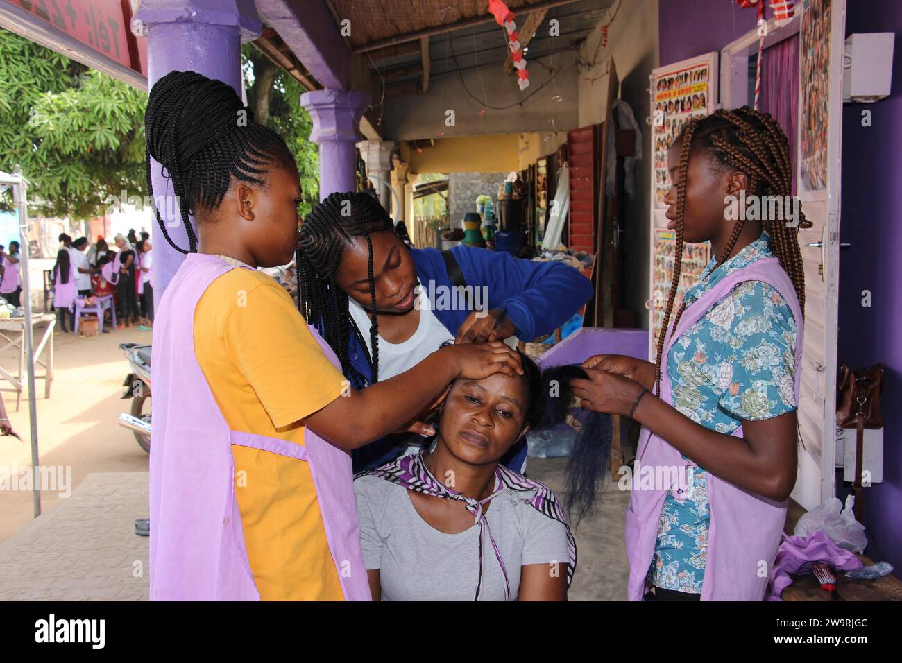 Ouidah, Benin. 29th Dec, 2023. Hairdressers braid a woman's hair in