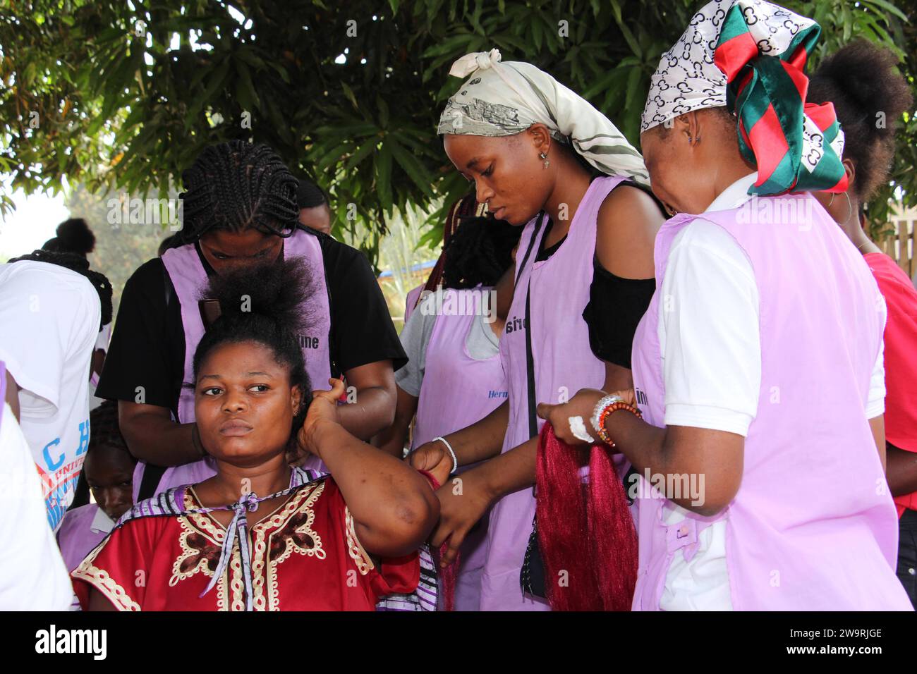Ouidah, Benin. 29th Dec, 2023. Hairdressers braid a woman's hair in