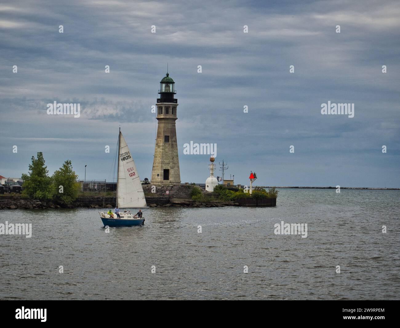 A sailboat passing in front of Buffalo Main Light lighthouse at the Marina on an overcast September day. Stock Photo
