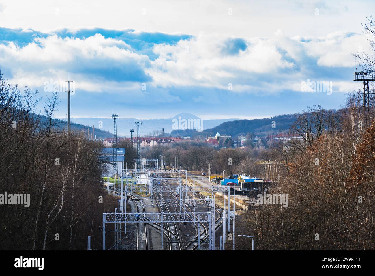 Train station in trees with a city and a mountain in a background Stock Photo