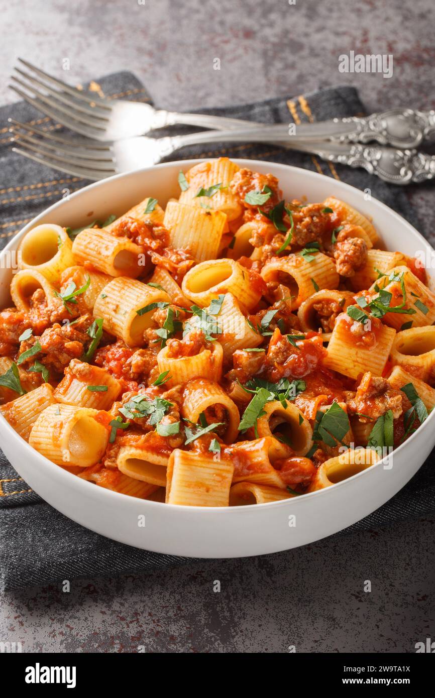 Italian pasta mezze maniche with bolognese sauce closeup on the plate on the table. Vertical Stock Photo