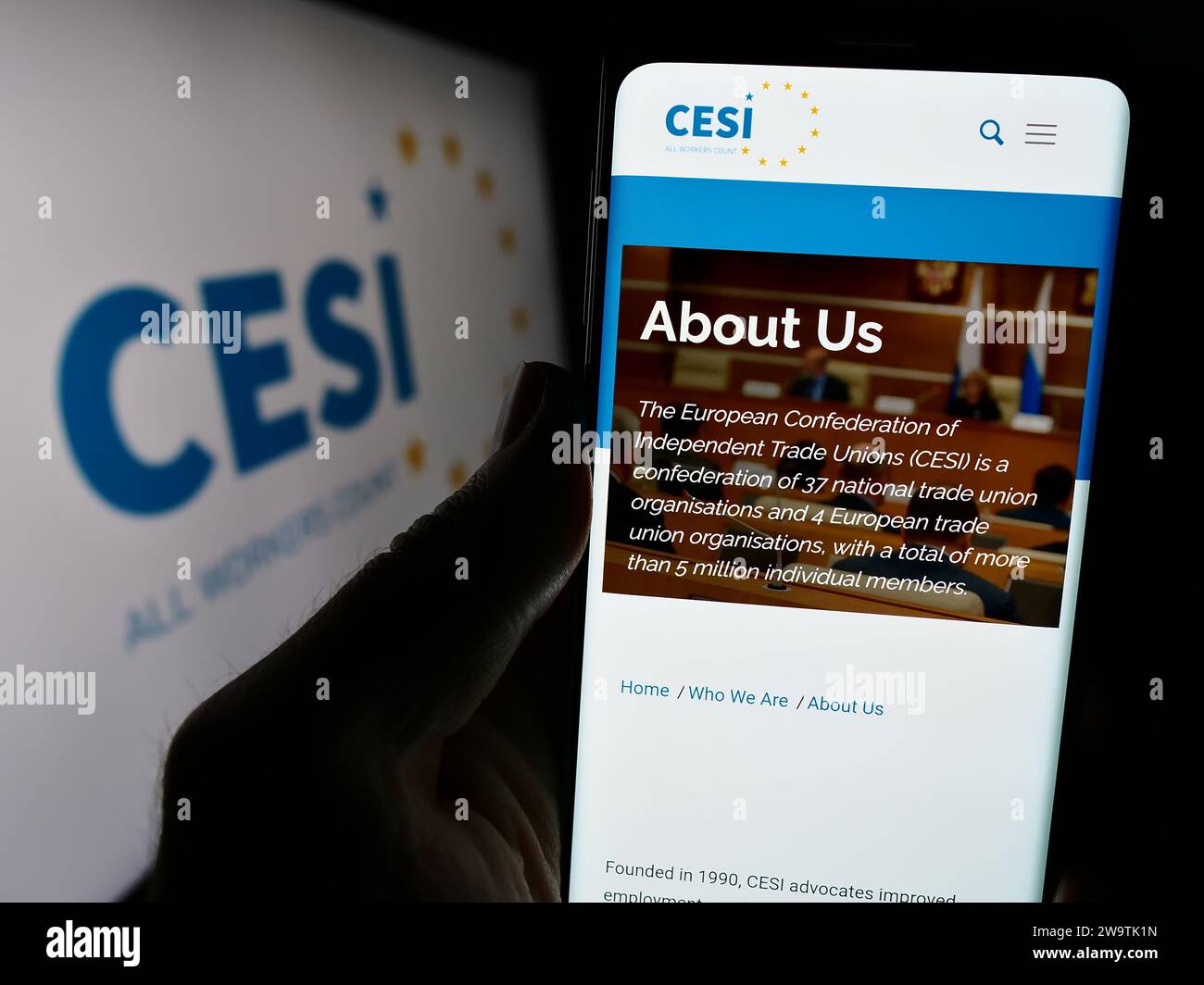Person holding cellphone with webpage of European Confederation of Independent Trade Unions (CESI) with logo. Focus on center of phone display. Stock Photo