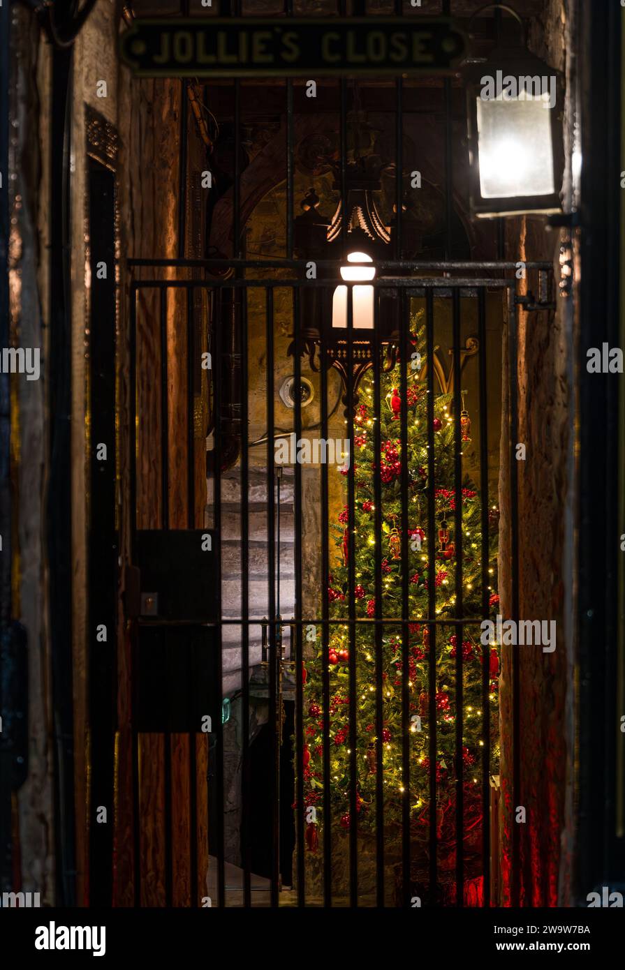 Christmas tree in alley off Royal Mile lit up at night with old fashioned street lamps, Edinburgh, Scotland, UK Stock Photo