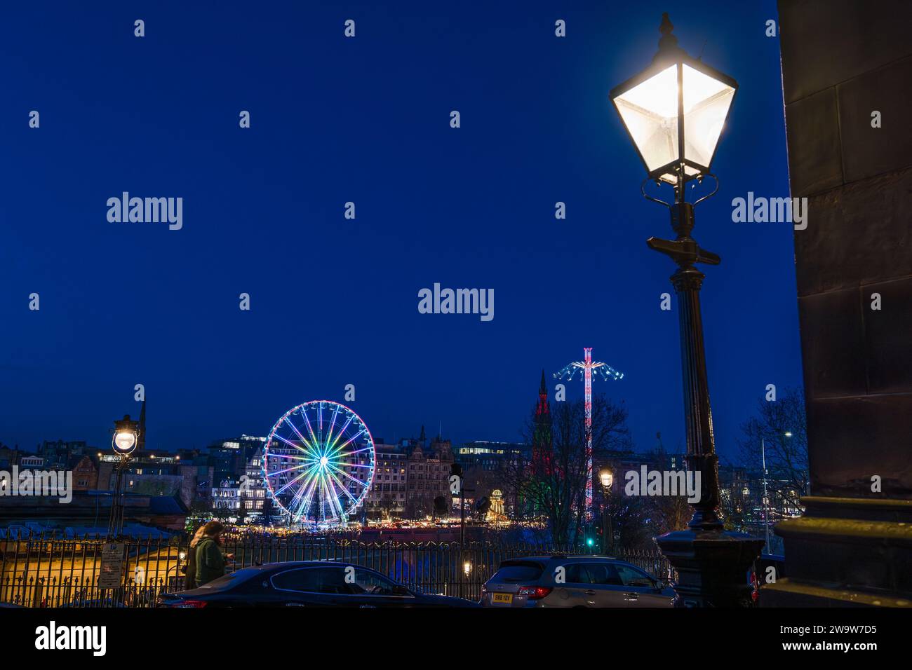 Big ferris wheel and star flyer fairground rides lit up at night at